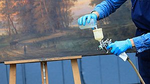 Restauratorin arbeitet mit Lackierpistole