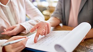 Hand zeigt in Unterlagen
