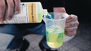 Mann gießt WAS 30 in Behälter