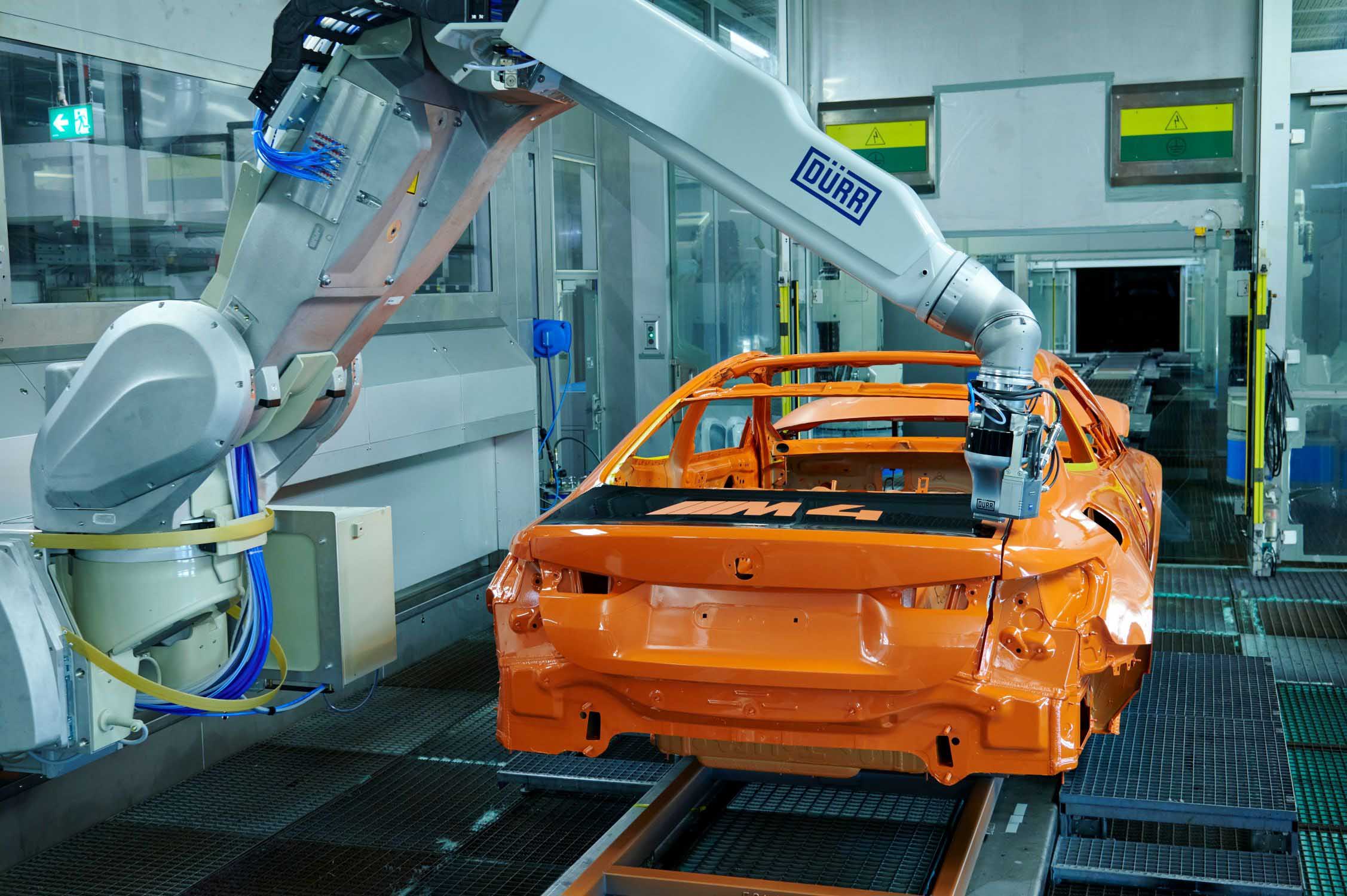 BMW M4 in der Lackierkabine, ein Roboter lackiert mit dem Dürr EcoPaintJet Pro ein Dekor auf die Kofferraumklappe.